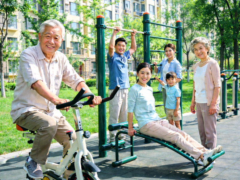 社区居民在崭新的社区健身器材上锻炼，笑容满面，背景绿树成荫